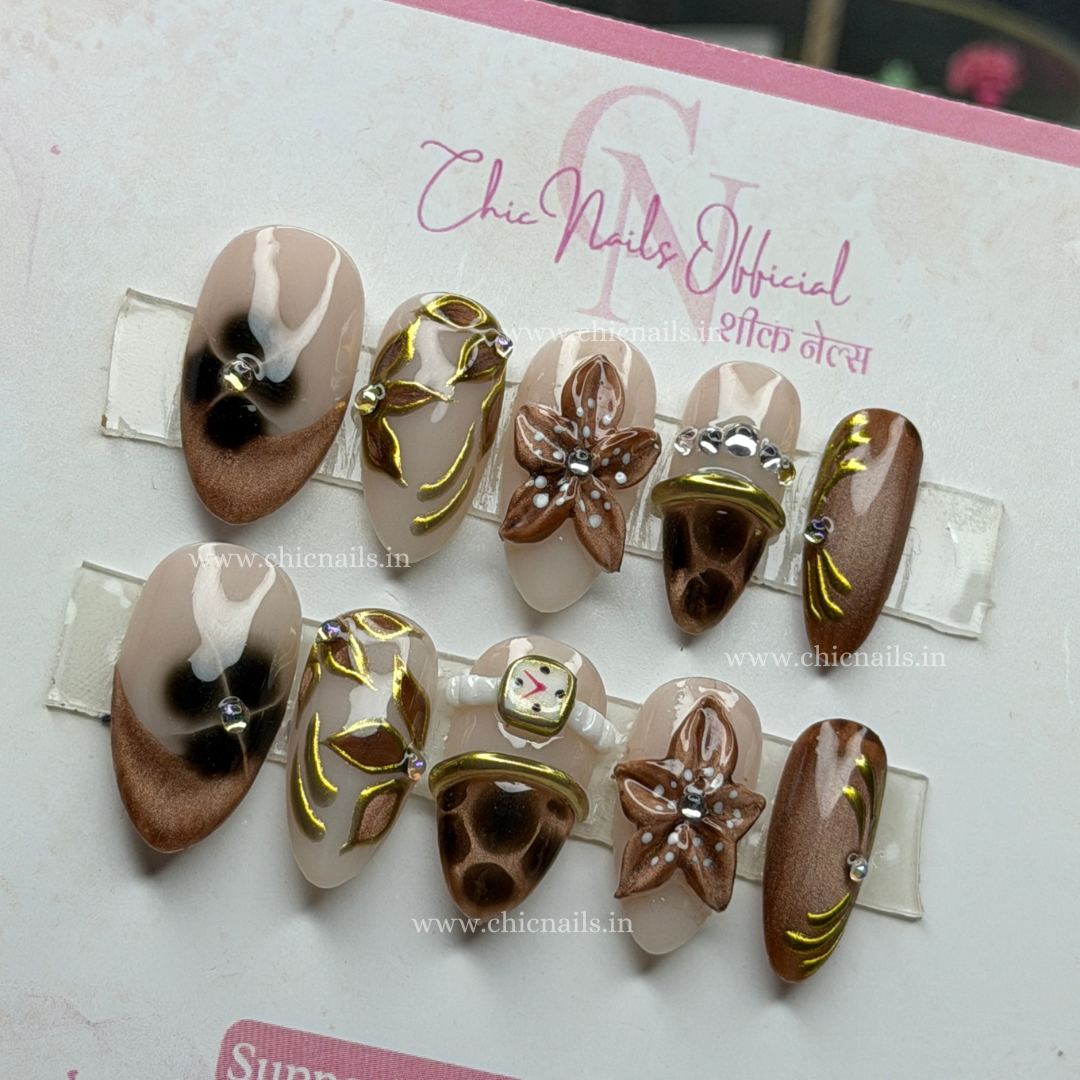Brown nude press-on nails with bangle nail art, 3D flower design, cat eye effect, chrome detailing, and elegant blossom accents by Chic Nails India