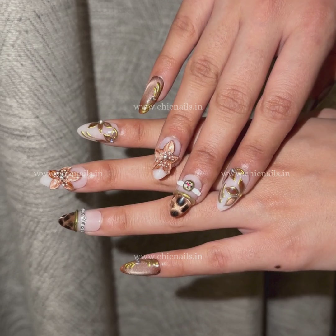 Brown nude press-on nails with bangle nail art, 3D flower design, cat eye effect, chrome detailing, and elegant blossom accents by Chic Nails India
