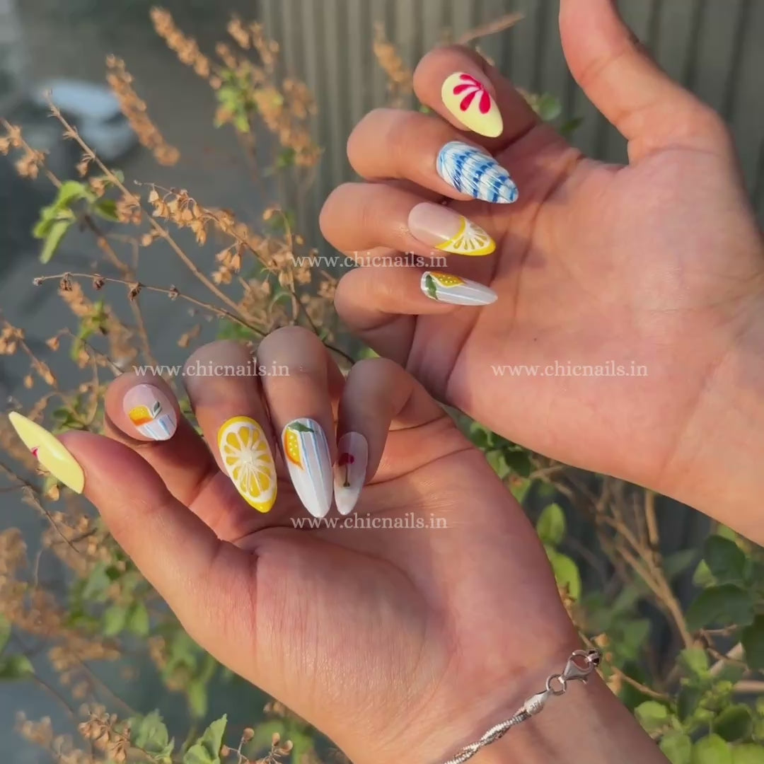 Summer Splash press-on nails with details of lemon, cherry, and ocean wave nail art in bright summer colors by chicnails India
