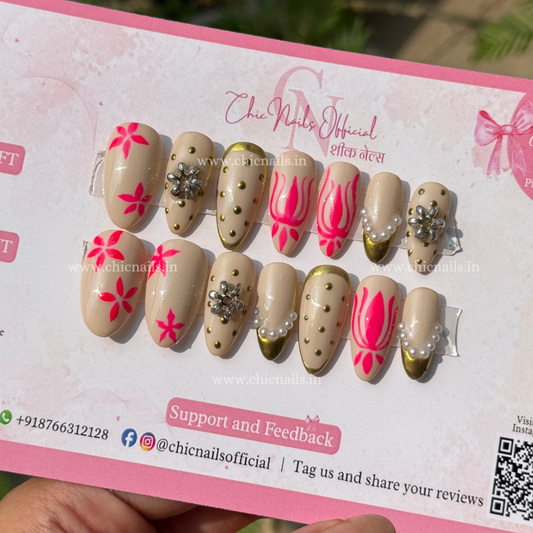 Riwaz Navratri press-on nails with pink floral motifs, gold detailing, pearls and jewellery-inspired embellishments by Chic Nails India