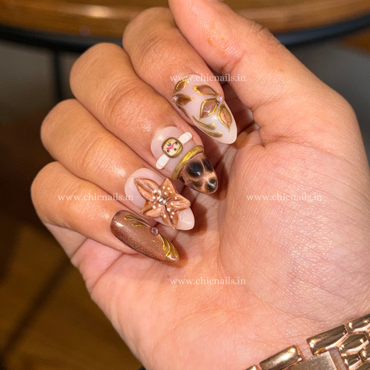 Brown nude press-on nails with bangle nail art, 3D flower design, cat eye effect, chrome detailing, and elegant blossom accents by Chic Nails India